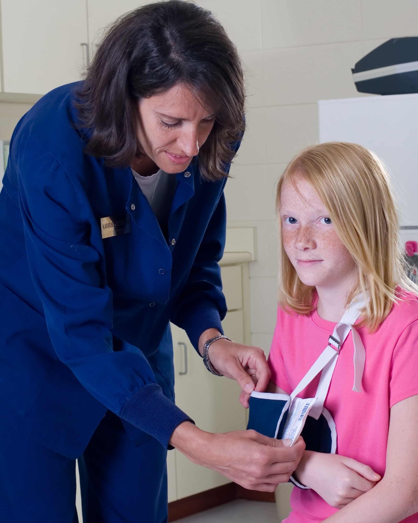 Image of a nurse adjusting a sling on a child.